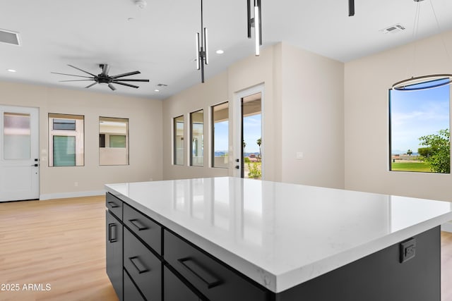 kitchen featuring ceiling fan, a kitchen island, light hardwood / wood-style floors, and decorative light fixtures