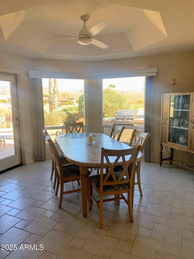 dining room with ceiling fan and a raised ceiling