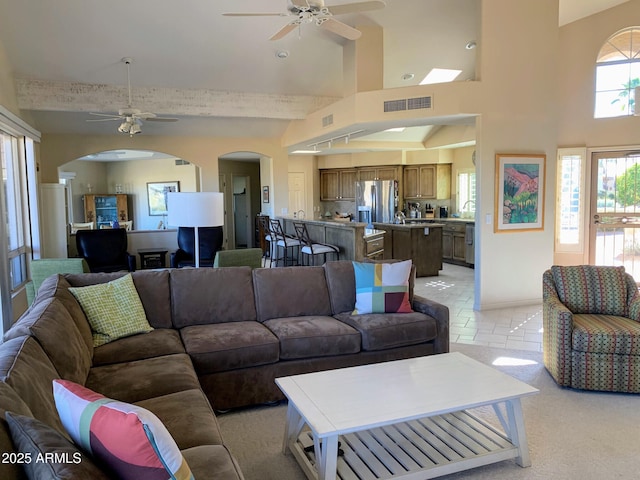 living room featuring sink, ceiling fan, and a high ceiling