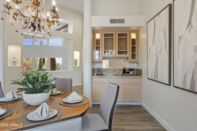 dining area with a towering ceiling, baseboards, visible vents, and dark wood-type flooring