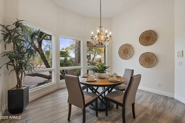 dining space with baseboards, a chandelier, a towering ceiling, and wood tiled floor