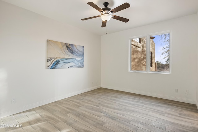 spare room featuring light wood finished floors, baseboards, and a ceiling fan