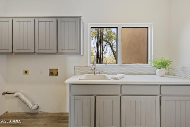 laundry area with washer hookup, cabinet space, a sink, electric dryer hookup, and wood finished floors