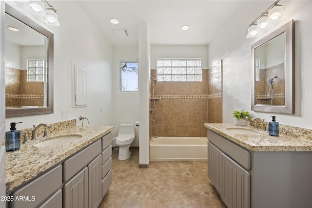 full bathroom featuring washtub / shower combination, two vanities, a sink, and toilet