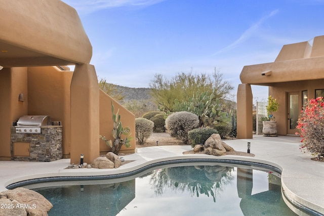 outdoor pool with a grill, an outdoor kitchen, and a patio