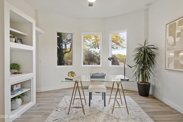 home office featuring wood tiled floor, built in shelves, and baseboards