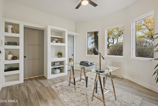 office with built in features, wood tiled floor, baseboards, and a ceiling fan