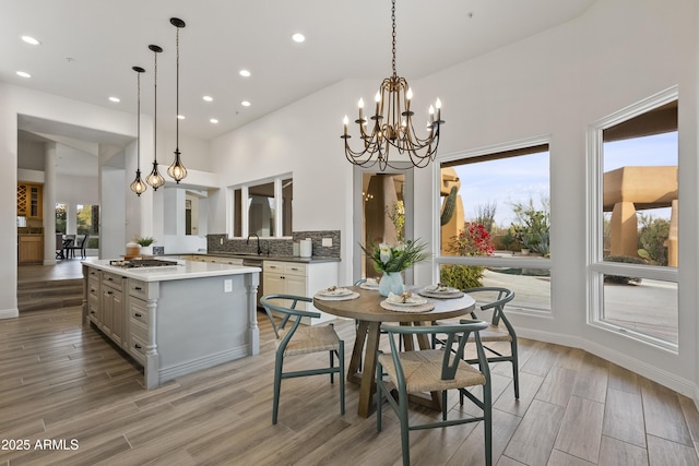 dining room featuring a chandelier, wood tiled floor, a towering ceiling, and recessed lighting