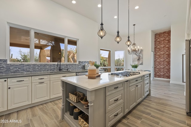 kitchen with tasteful backsplash, a center island, wood finish floors, open shelves, and a sink