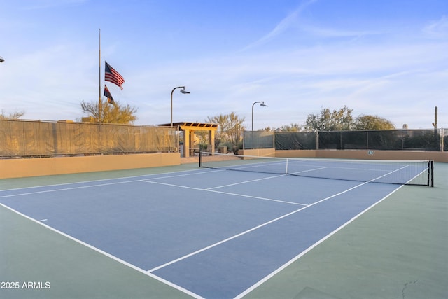 view of tennis court with fence and a pergola