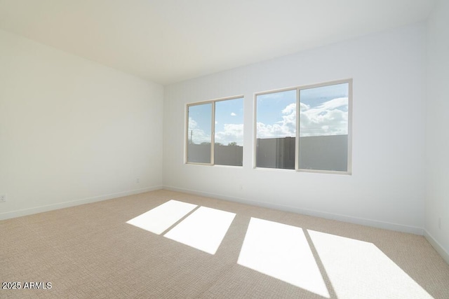 unfurnished room with baseboards and light colored carpet