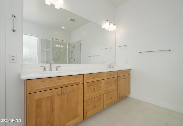 full bathroom with double vanity, a stall shower, baseboards, and a sink