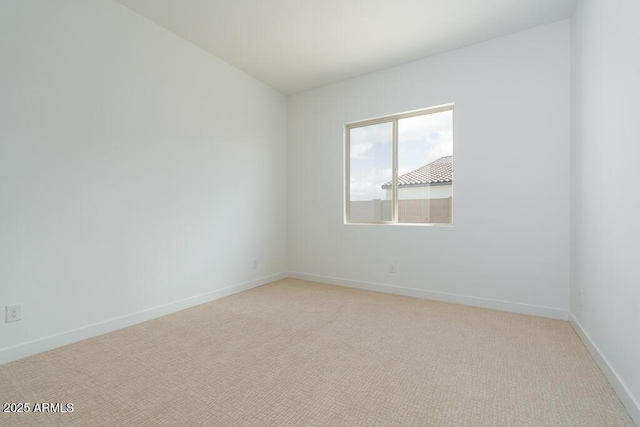 unfurnished room with baseboards and light carpet