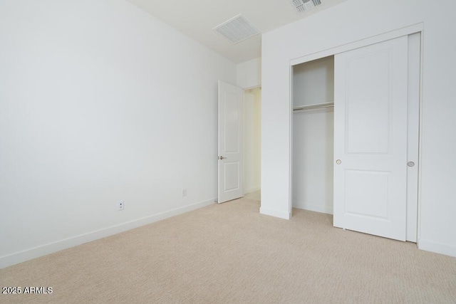 unfurnished bedroom featuring baseboards, visible vents, light carpet, and a closet