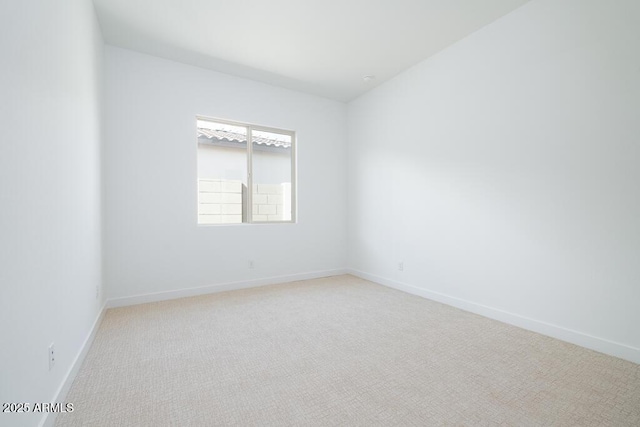 unfurnished room with baseboards and light carpet