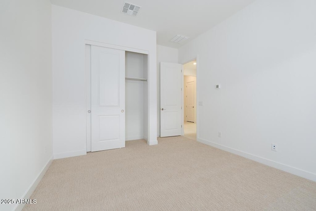 unfurnished bedroom featuring light colored carpet, visible vents, a closet, and baseboards