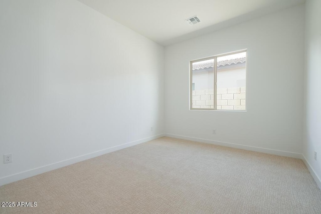 empty room featuring light carpet, visible vents, and baseboards