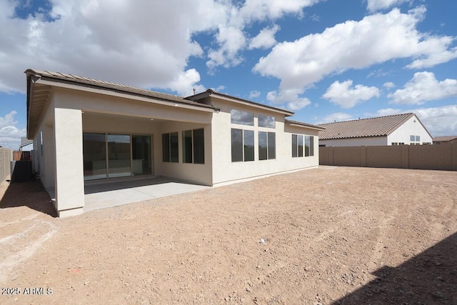 rear view of property featuring stucco siding, a patio, and a fenced backyard