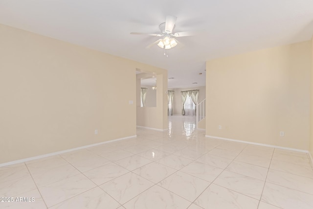 unfurnished room with ceiling fan and baseboards