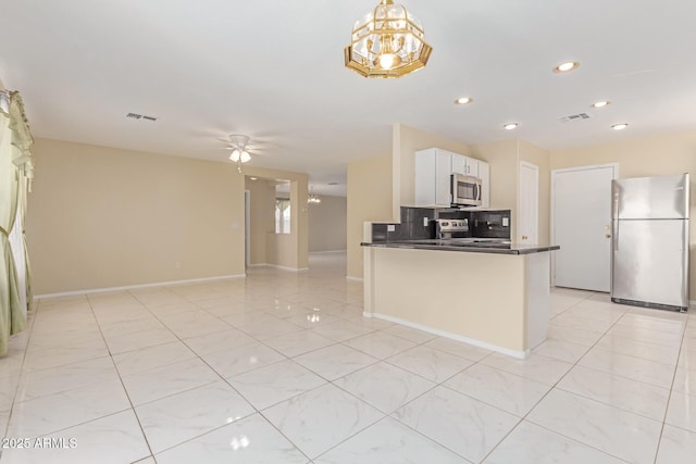 kitchen with stainless steel appliances, visible vents, decorative backsplash, and dark countertops