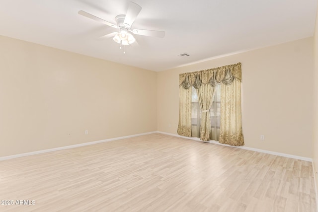 spare room with light wood-style floors, ceiling fan, and baseboards