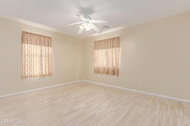 empty room featuring light wood-style flooring, baseboards, and plenty of natural light