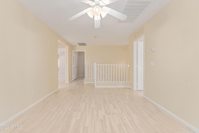empty room featuring light wood finished floors, visible vents, baseboards, and a ceiling fan