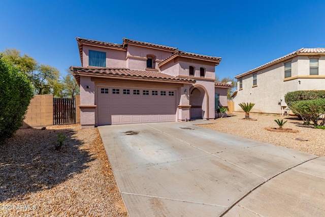 mediterranean / spanish-style home with a tiled roof, a garage, stucco siding, fence, and concrete driveway
