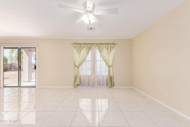 tiled spare room with visible vents, baseboards, and ceiling fan