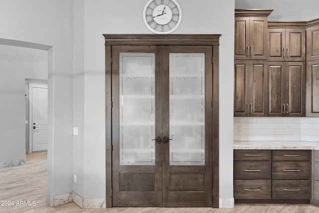 interior space featuring light hardwood / wood-style flooring, light stone countertops, and dark brown cabinetry