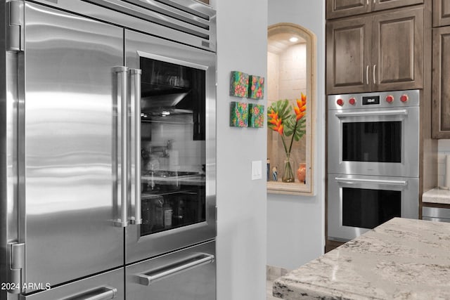 kitchen featuring dark brown cabinetry, appliances with stainless steel finishes, and light stone countertops