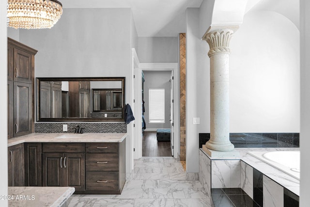 interior space featuring tiled bath, vanity, and decorative columns