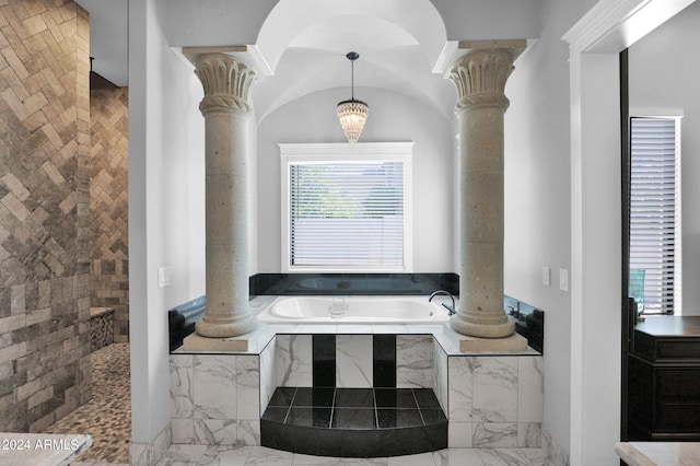 bathroom featuring ornate columns and tiled bath