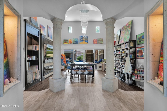 interior space with decorative columns, hardwood / wood-style floors, and a notable chandelier