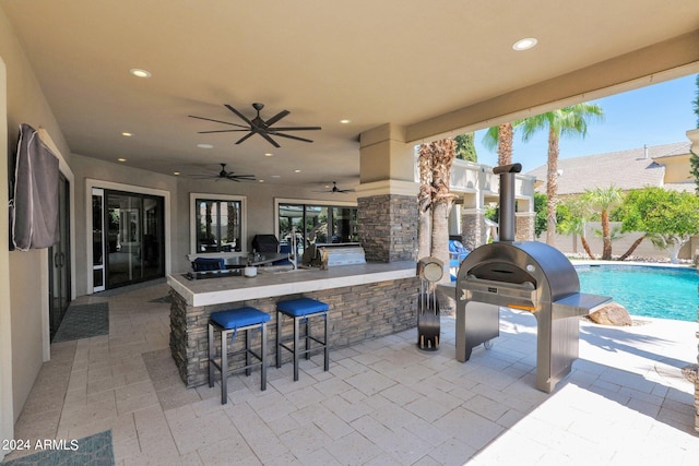 view of patio featuring a bar, ceiling fan, and an outdoor kitchen