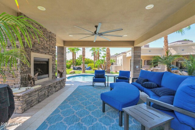 view of patio / terrace with ceiling fan and an outdoor living space with a fireplace