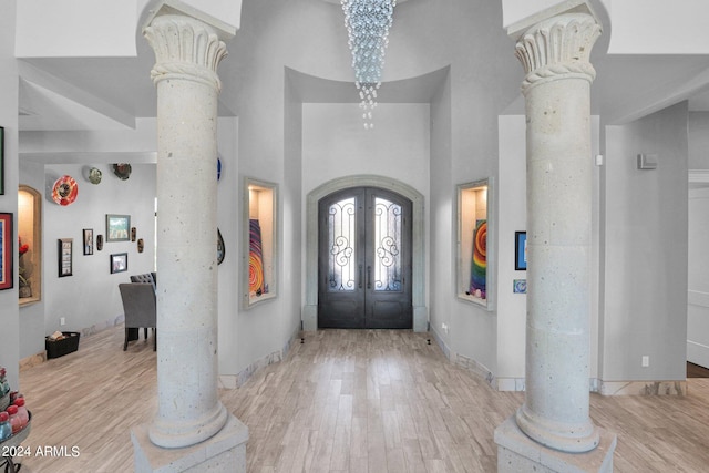 entrance foyer with a high ceiling, an inviting chandelier, light hardwood / wood-style floors, and french doors