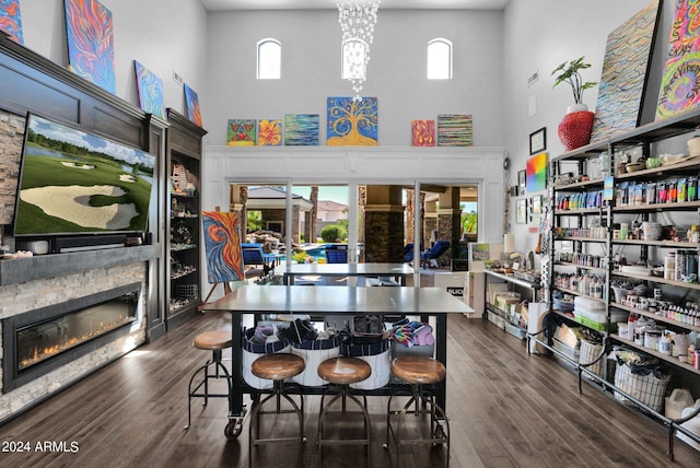 dining area featuring a fireplace, a towering ceiling, a healthy amount of sunlight, and dark hardwood / wood-style floors