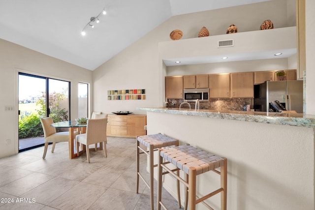 kitchen featuring kitchen peninsula, light brown cabinetry, high vaulted ceiling, and appliances with stainless steel finishes