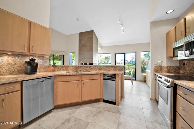 kitchen with light stone countertops, sink, high vaulted ceiling, kitchen peninsula, and appliances with stainless steel finishes