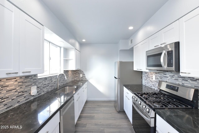 kitchen featuring dark stone countertops, stainless steel appliances, sink, and white cabinets