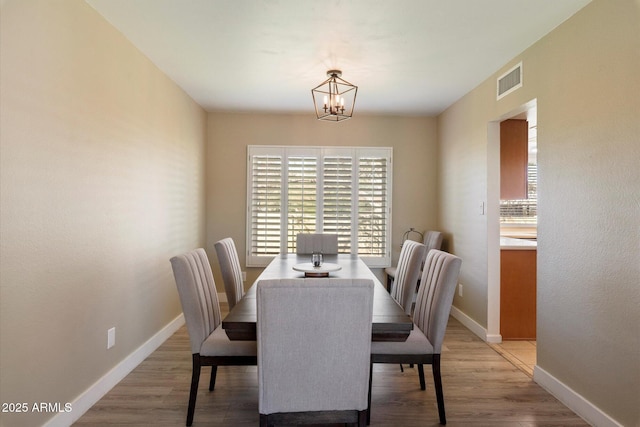 dining area with wood-type flooring and a chandelier