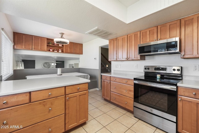 kitchen featuring a textured ceiling, light tile patterned floors, and appliances with stainless steel finishes