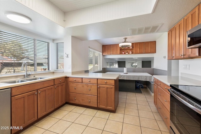 kitchen with sink, stainless steel appliances, kitchen peninsula, and light tile patterned flooring