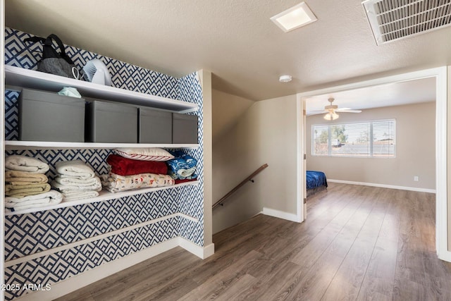 stairs featuring hardwood / wood-style flooring, a textured ceiling, and ceiling fan