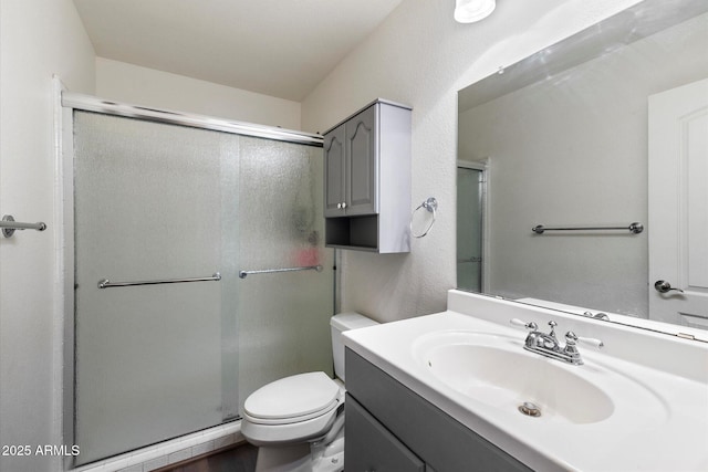 bathroom with a shower with door, toilet, and vanity