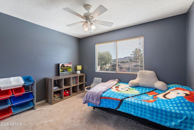 carpeted bedroom with ceiling fan and a textured ceiling