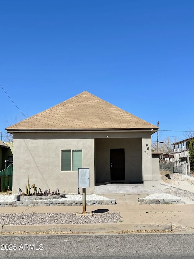 view of side of property with a shingled roof and stucco siding