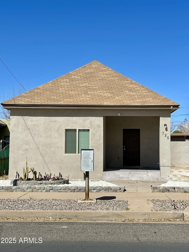 back of property featuring stucco siding and roof with shingles