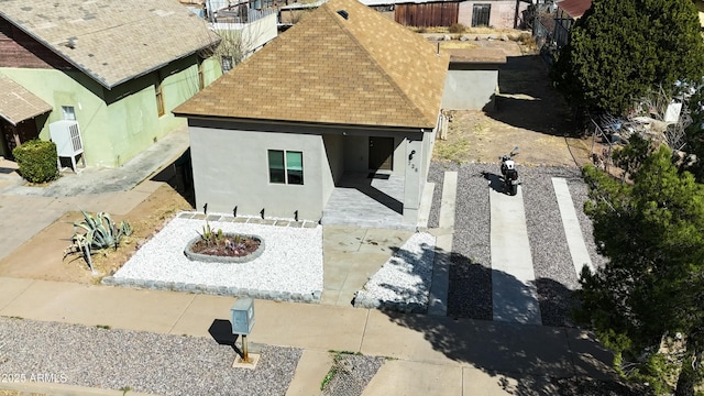 exterior space featuring a patio area, a shingled roof, fence, and stucco siding